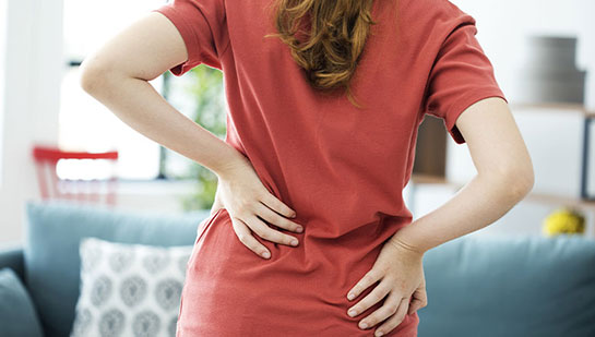 Woman holding lower back in pain before visiting Ohio chiropractor