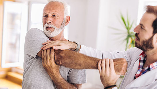 Elderly man receiving shoulder adjustment from Ohio chiropractor
